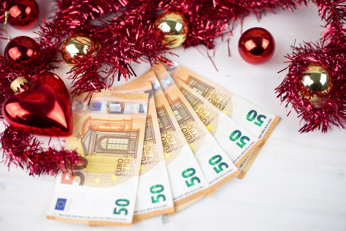 christmas-money-business-concept-some-fifty-euro-banknotes-with-red-and-gold-baubles-and-wreath-decoration-on-light-wooden-table-stockpack-istock Christmas money business concept: some fifty euro banknotes with red and gold baubles and wreath decoration on light wooden table