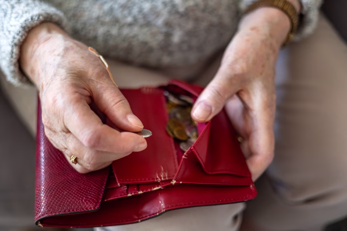 Close-up of an elderly woman’s hands holding a wallet with coins