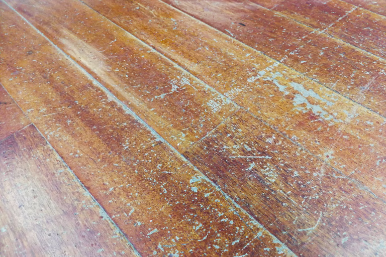Corroded and damaged seasoned wooden floor plank with scratch marks needs restoration