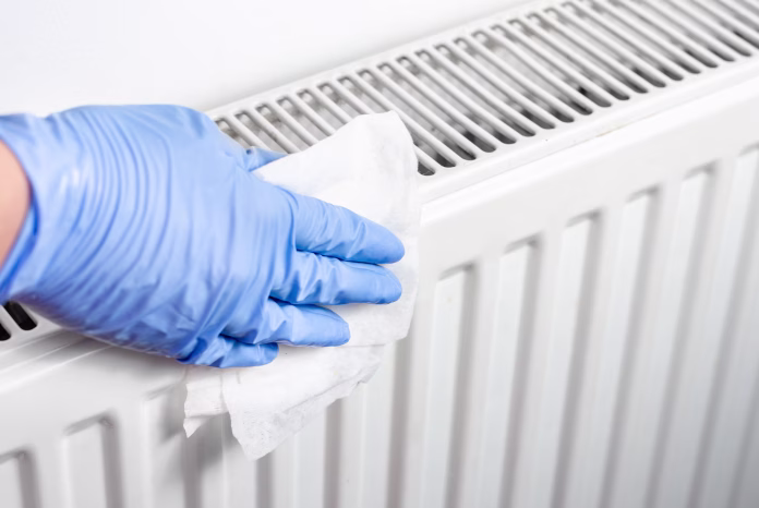 Man with surgical gloves cleaning the radiator with disinfectant wet wipes . Preventing of bacteria and coronavirus spreading .