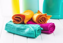 Ali lahko krpo iz mikrovlaken dajemo v sušilni stroj? Microfiber cleaning towels on white table.