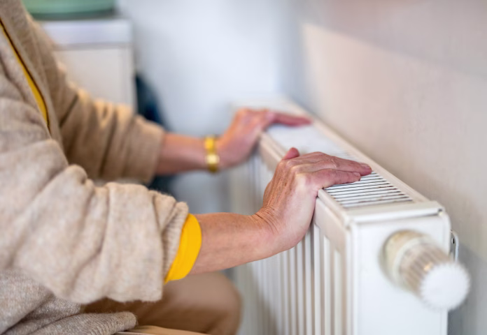 Senior woman checking heating radiator in her apartment