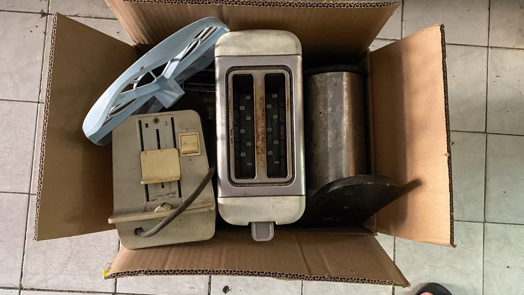 Throw away old kitchen appliances. Disposal of electrical appliances in the card box. Find it in the trash. Throw the bread toaster in the trash.