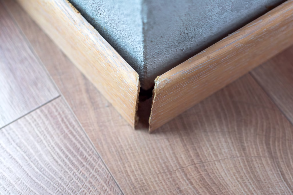 Broken wooden skirting revealing the cracks and imperfections along the edge. The image highlights issues related to home maintenance and the effects of wear and damages over time