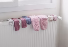 Sušenje oblačil na radiatorju »ubija« pljuča: dramatično opozorilo strokovnjaka, bodite previdni Colorful woolen socks drying on a radiator heater in home. Winter time, cold weather lifestyle.