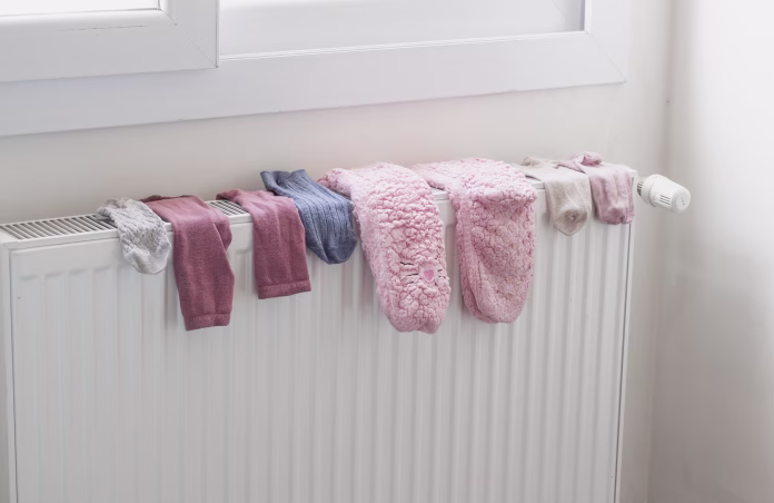 Colorful woolen socks drying on a radiator heater in home. Winter time, cold weather lifestyle.
