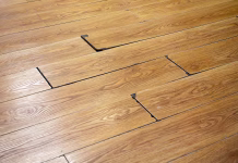 5 znakov, da je treba zamenjati talne obloge Fragment of damaged inexpensive laminate flooring.