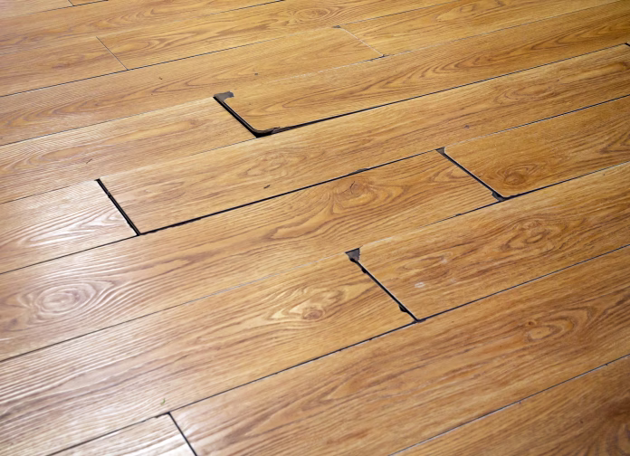 Fragment of damaged inexpensive laminate flooring.