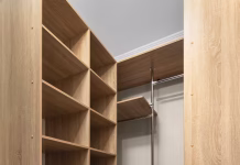Vgradne omare pod povečevalnim steklom FURS: mizarji pred davčnim preplahom … Interior of a dressing room with a built-in wooden storage system and empty shelves.