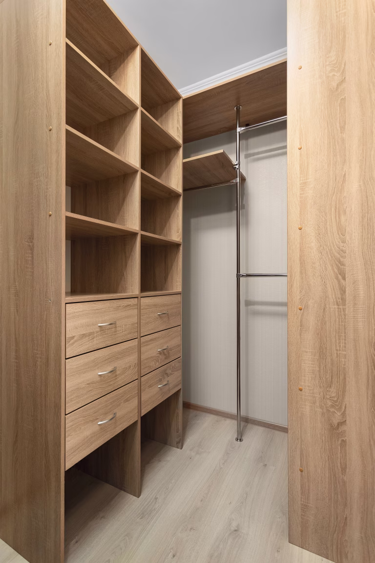 Interior of a dressing room with a built-in wooden storage system and empty shelves.