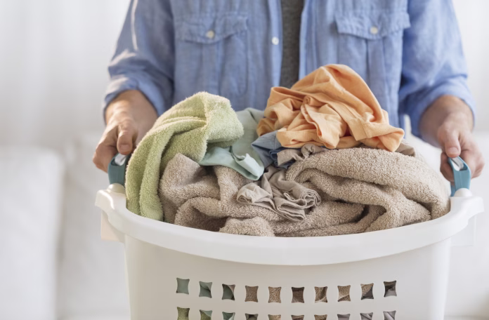 Midsection of mature man holding laundry basket at home