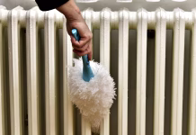 Znižajte račune! 2 preprosta trika z radiatorjem, ki prihranita denar to zimo older woman clean radiator with brush for new season, from dust