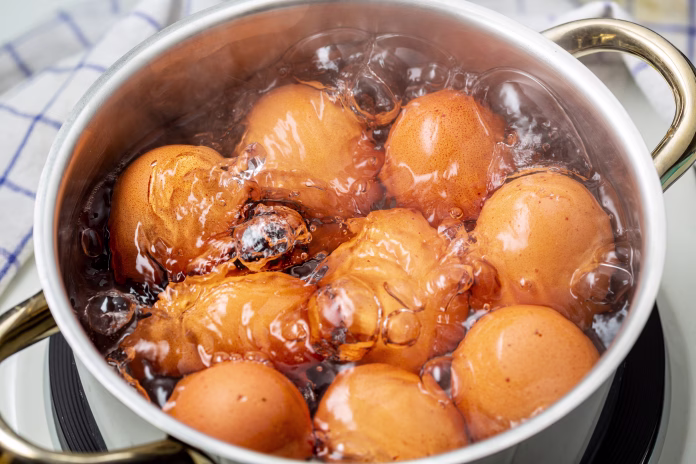 cooking brown chicken eggs in boiling water on electric stove, closeup, elevated view