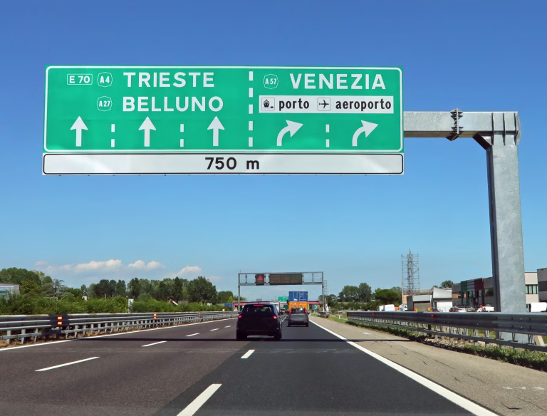 Motorway junction with large sign with directions to major cities in Italian such as Venice and the airport
