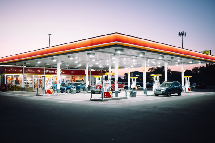 Toledo Ohio, United States – September 19, 2024: A brightly lit gas station at dusk with cars refueling and a convenience store in the background.