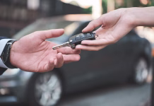 Strokovnjak svetuje: Če se vam na rabljenem avtu prižge ta lučka, ga takoj prodajte! Car dealership.Young man receiving car key from saleswoman.
