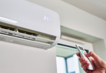 Tipka na klimi, za katero redki vedo, tiho »reže« račun za elektriko in ogreje dom bolj, kot si lahko predstavljate … Hand adjusting temperature on air conditioner with remote control, Working air conditioner for comfort temperature in home at hot summer