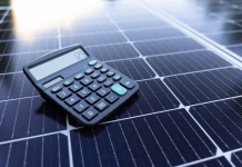 Samooskrba s sončno energijo v letu 2026: pot v trajnostno prihodnost Image of a calculator on a solar panel representing the concept of saving energy with renewable energy