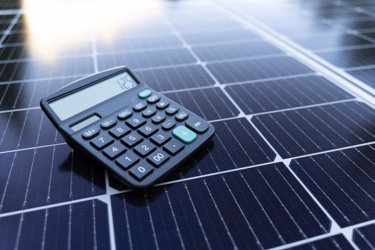 Image of a calculator on a solar panel representing the concept of saving energy with renewable energy