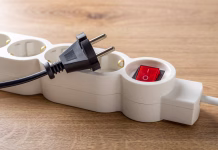 Pasti izklapljanja iz vtičnice: pri treh napravah bodite še posebej previdni Unplugged electric appliance plug over switched off white power strip on the floor. Power crisis. Increasing the energy costs, heating costs, save electricity concepts. Power outage. Close-up.