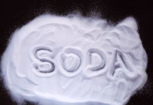 Najbolj uporabni načini uporabe sode bikarbone v domu (10/30) White powder sprinkled on a dark surface with the letters "Soda" painted on it. View from above.