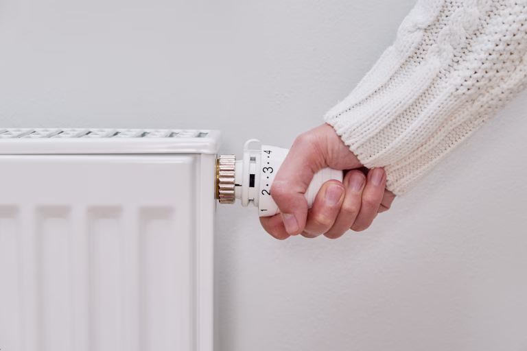 Woman adjusting temperature on heating radiator, Energy crisis concept in Europe, Rising costs in private households for gas bill due to inflation and war