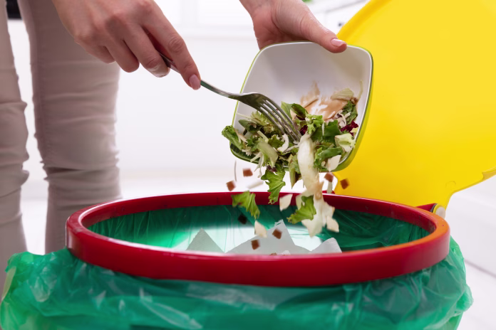 Close-up Of A Woman's Hand Throwing Vegetables In Trash Bin
