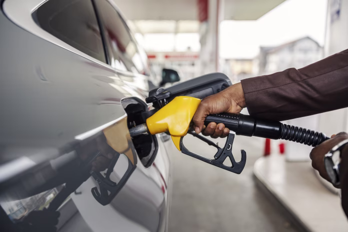 Cropped picture of an unrecognizable diverse man's hand holding nozzle and filling up the tank at gas station.