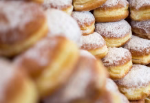 Ali poznate tri osnovna pravila dobrega krofa? Morda je videti preprost, a napak ne odpušča Donuts with no holes, a traditional deep fried dough sprinkled with powdered sugar, filled with marmalade and stacked for display. Photographed with shallow depth of field and more donuts in the foreground.