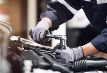 Mehaničarka razkriva: To so znaki, da vas goljufajo in vam popravilo avta zaračunajo kot suho zlato Mechanic works on the engine of the car in the garage. Repair service. Concept of car inspection service and car repair service.