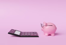 Varčevanje denarja: med zdravo pametjo in majhnimi skušnjavami Pink piggy bank wearing spectacles in front of a black calculator on pink background. Illustration of the concept of commercial accounting, income calculation and retirement planning