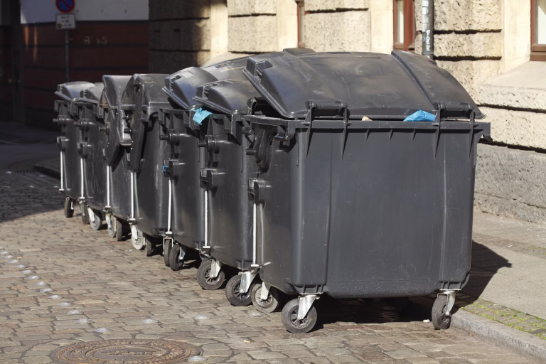 Recycling bins, black garbage containers for residual waste standing on the sidewalk