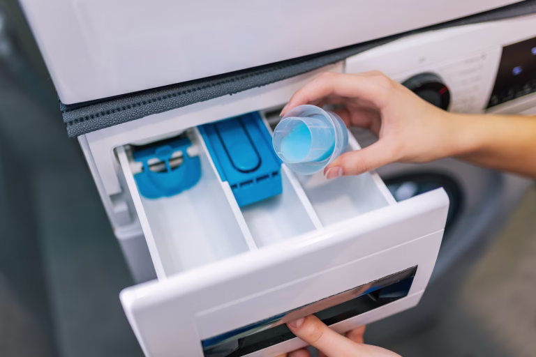 Woman puts softener in the washing machine.