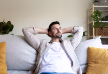 Kako znižati mesečne stroške, če živite sami? Young man enjoys a moment of tranquility at home, resting on his comfortable sofa