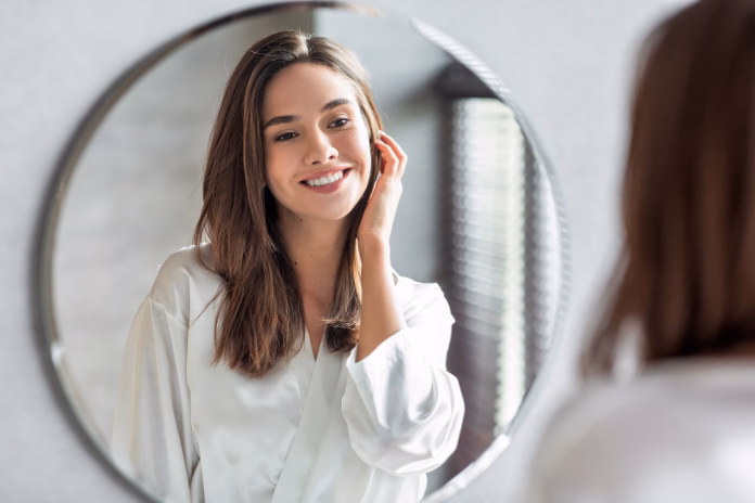 beauty-concept-portrait-of-attractive-happy-woman-looking-at-mirror-in-bathroom-beautiful-millennial-lady-wearing-white-silk-robe-smiling-to-reflection-enjoying-her-appearance-selective-focus-stockpack-istock Beauty Concept. Portrait Of Attractive Happy Woman Looking At Mirror In Bathroom, Beautiful Millennial Lady Wearing White Silk Robe Smiling To Reflection, Enjoying Her Appearance, Selective Focus