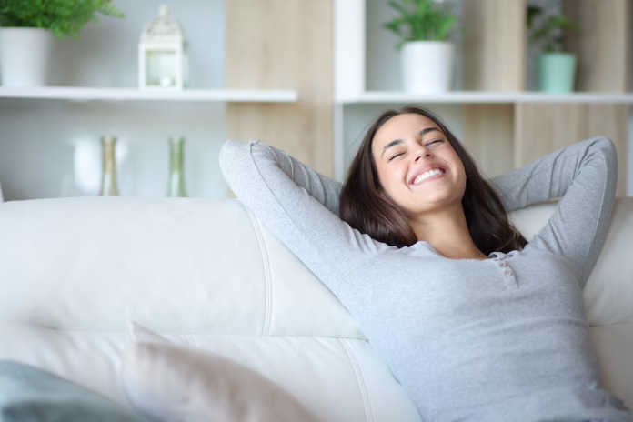Happy woman resting sitting in a comfortable couch at home