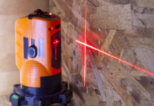 Kako uporabljati laserski nivelir in se izogniti največjim napakam? laser measurement level for construction works, small depth of sharpness, focus on a wall with a tag