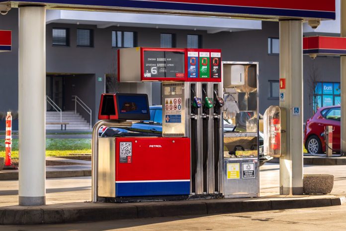 Ljubljana, Slovenia December 30, 2025, fuel pump at gas station, a close-up view of a modern fuel pump at a gas station with multiple nozzles for different fuel types, digital display showing price and liters, and safety signs visible, with cars and buildings in the background