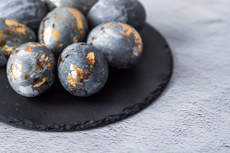 Stylish grey Easter eggs made of marble and concrete with a golden potala on a grey background. Coloring eggs with natural dye karkade tea. The concept of a happy Easter.