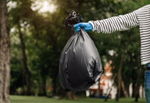 Generalno čiščenje: teh 8 stvari takoj vrzite iz doma, ne bo vam žal! Hand holding garbage black bag putting in to trash to clean. Clearing, pollution, ecology and plastic concept.