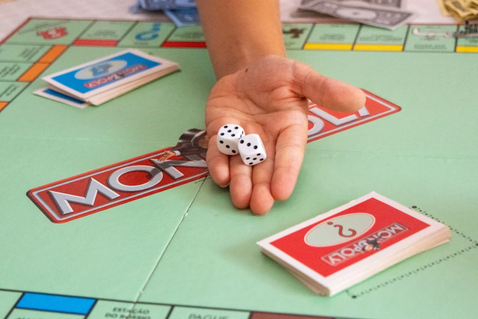 Lisbon, Portugal, August 31, 2025, Kid holding dice while playing monopoly board game, with money and cards visible on the table
