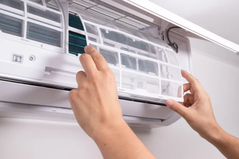 Close up of man inserting new filter into air conditioner unit during regular maintenance. Concept of HVAC service, home care, clean indoor air, and energy-efficient cooling.