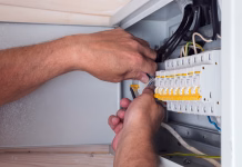 Gumb na razvodni tabli preprečuje požar: Nihče ga ne preverja niti ve, katero oznako ima! Electrician's hands skillfully connecting cables in an open distribution board, focusing on quality and precision for safe power usage.