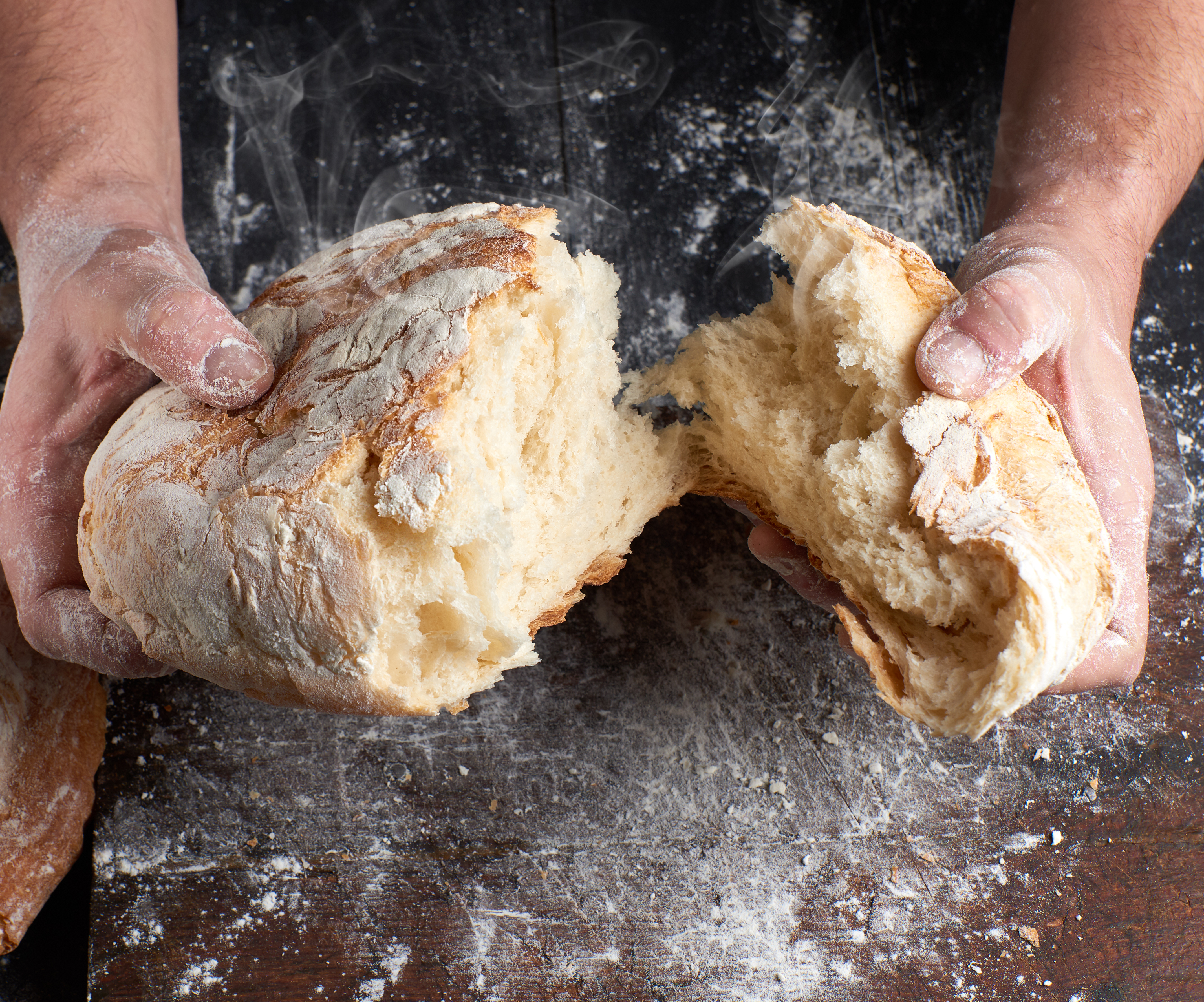 To boste od zdaj naprej vsakič preverili! Tako boste vedeli, ali vam prodajajo »zamrznjen« ali svež kruh. male hands breaking open baked bread in half over black wooden table