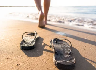 Za nošenje te poletne obutve kazen 2500 evrov! Inšpektorji na priljubljeni destinaciji začenjajo nadzor Woman's legs move away from their sandals towards the sea water on a beach