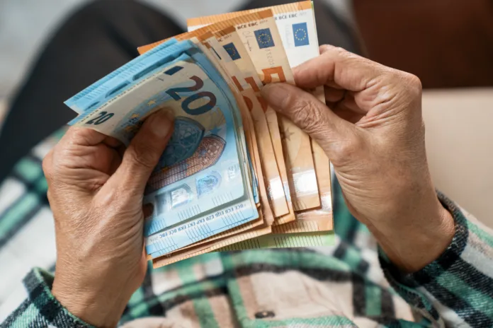 a-bundle-of-euros-in-the-hands-of-an-elderly-pensioner-the-concept-of-financial-security-in-old-age-stockpack-istock A bundle of euros in the hands of an elderly pensioner. The concept of financial security in old age.