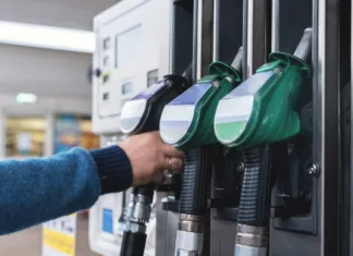 To so nove cene goriv: nekateri z njimi ne bodo zadovoljni A customer interacts with fuel pumps at a gas station, engaging in refueling their vehicle while surrounding areas are busy and well-maintained during daylight.