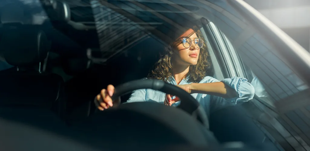 Beautiful young happy smiling woman driving her new car. Buying and renting a car. Travel, tourism, recreation.