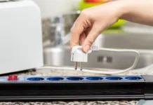 Ti trije kuhinjski aparati se nikoli ne smejo priključiti na podaljšek: zato najpogosteje pride do požarov Close up of a woman's hand plugging a toaster into the electrical outlet in a socket on a kitchen counter at home