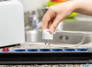 Ti trije kuhinjski aparati se nikoli ne smejo priključiti na podaljšek: zato najpogosteje pride do požarov Close up of a woman's hand plugging a toaster into the electrical outlet in a socket on a kitchen counter at home